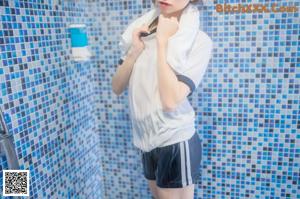 a woman standing in front of a blue tiled wall