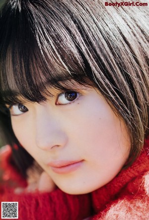 A woman in a red sweater laying on a bed.