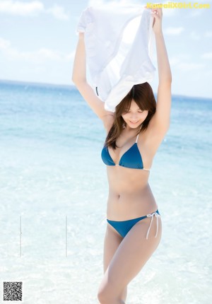 A woman in a blue bikini standing on a beach.