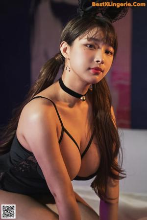 A woman in a black lingerie leaning against a wall.