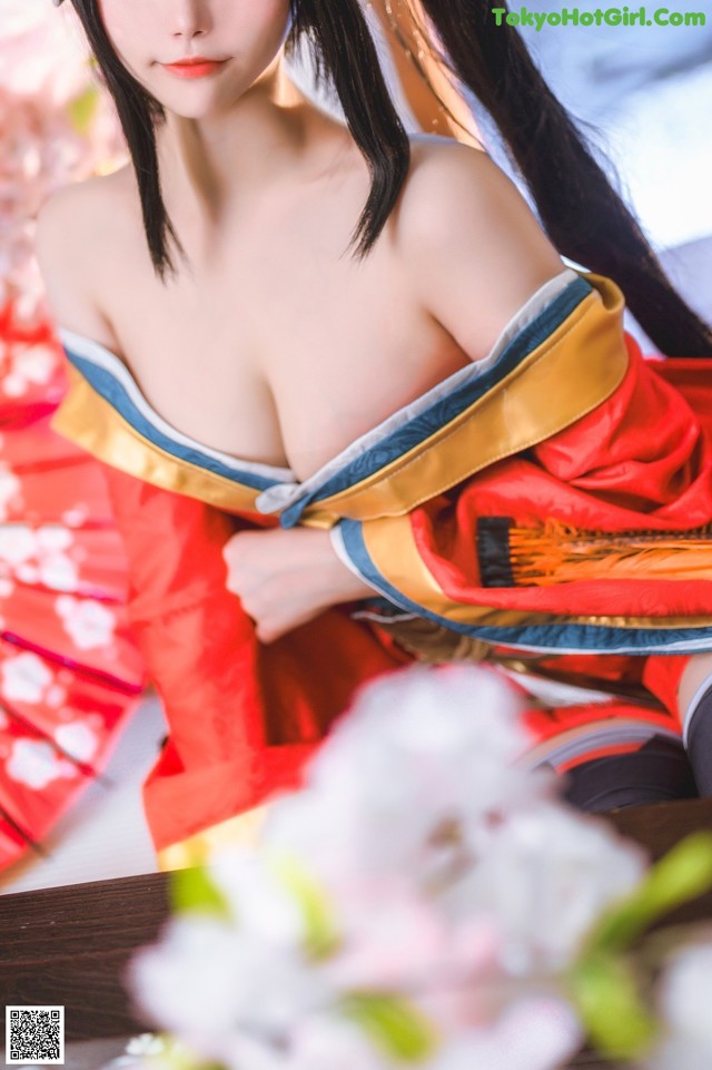 A woman in a red and yellow kimono sitting on a table.