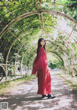 A woman in a red dress standing in front of flowers.
