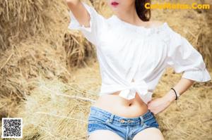 A woman in a cowboy hat standing on a pile of hay.