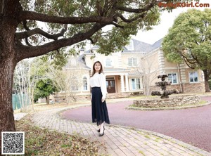 A woman in a white blouse and black skirt posing for a picture.