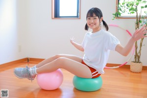 A woman in a white shirt and red shorts holding a hula hoop.