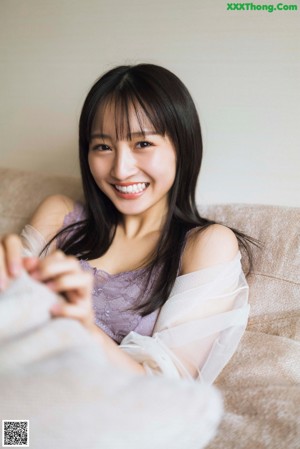 A woman sitting on a bed holding a cell phone.