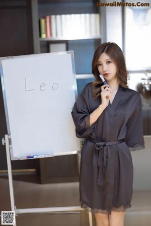 A woman sitting on a chair in front of a white board.