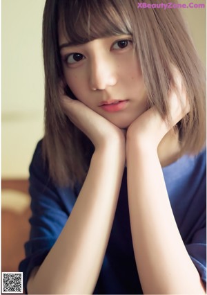 A woman in a white shirt leaning against a wall.