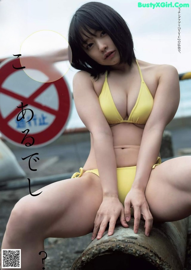 A woman in a yellow bikini sitting on a pipe.