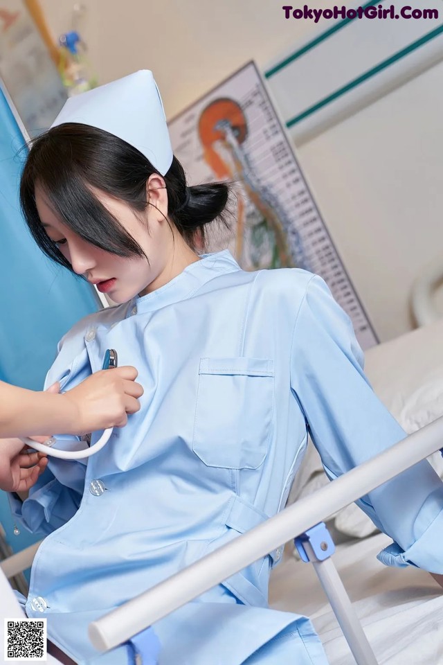 A woman in a blue uniform is holding a stethoscope.