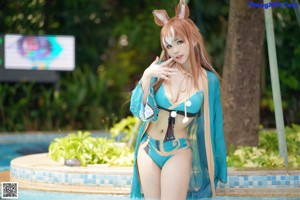 A woman in a bikini sitting on the edge of a pool.