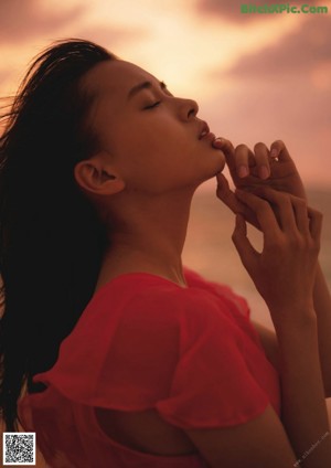 A woman sitting on the floor drinking from a glass.