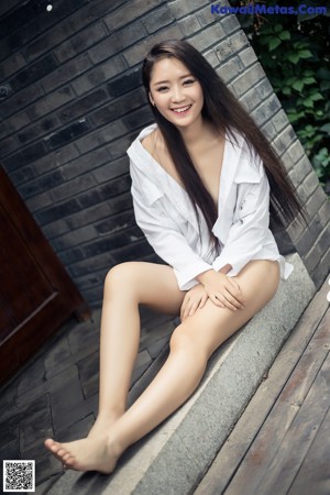 A woman sitting on a wooden deck holding a cup of coffee.