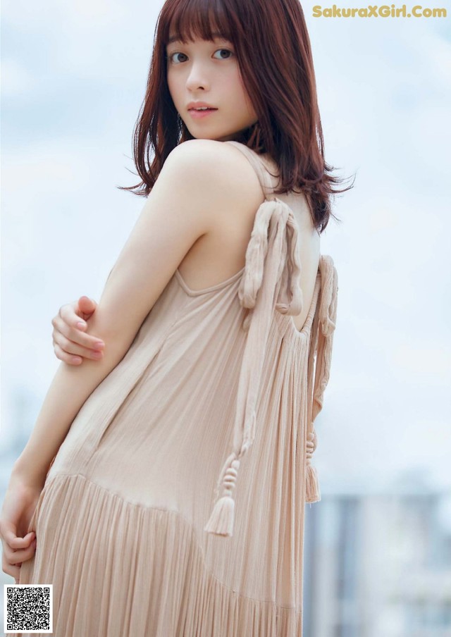 A woman in a beige dress is posing for a picture.