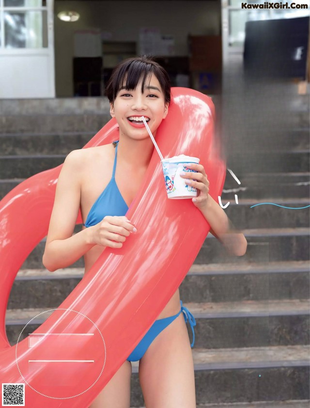 A woman in a blue bikini holding a cup of ice cream.