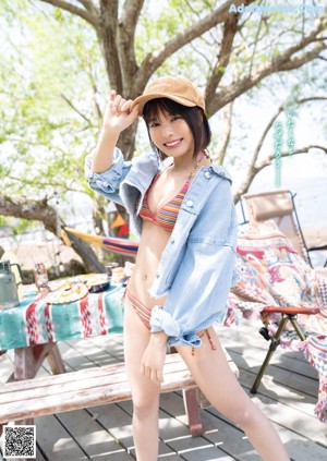 A woman in a bikini sitting on a tree branch.