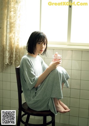 A woman in a blue dress standing in front of a window.