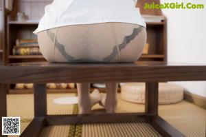 A woman in a white shirt and pantyhose sitting on a wooden bench.