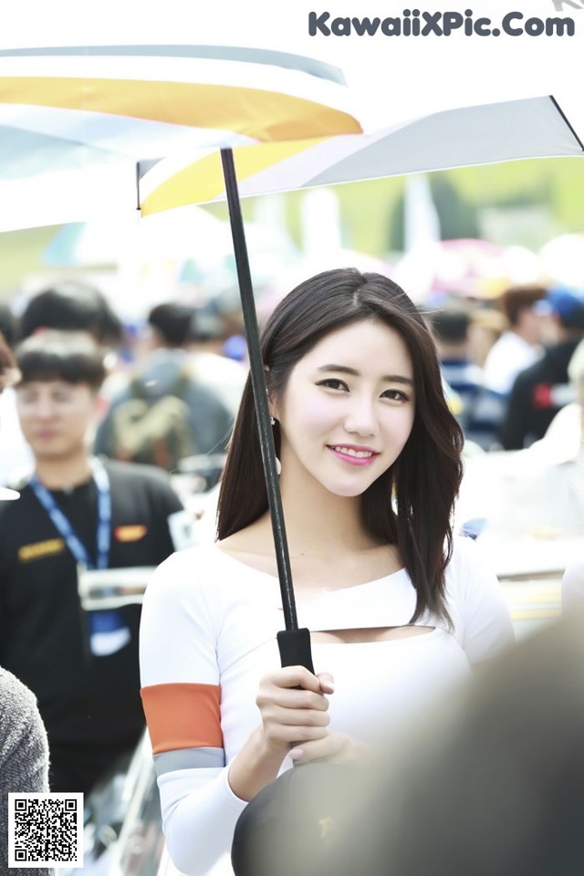 A woman holding an umbrella in front of a crowd.