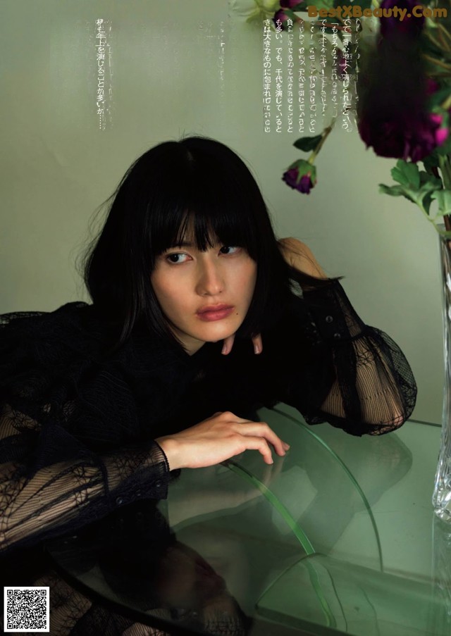 A woman sitting at a table with a vase of flowers.