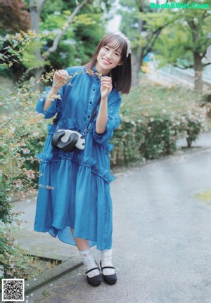 A woman standing in front of a window wearing a white dress.