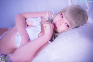 A woman in a white bikini sitting on a bed.