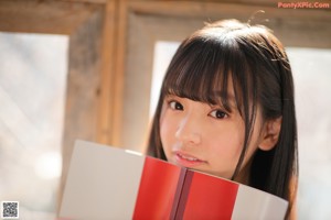 A young woman sitting on a couch holding a book.